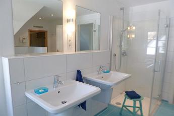 Das Bad im OG mit walk in Dusche ist farblich ansprechend gestaltet und zeigt ein modernes ansprechendes Ambiente.