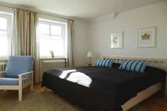 Das helle behagliche Schlafzimmer mit Doppelbett (180x200 cm), zwei Sesseln und einer kleinen Schreibablage.